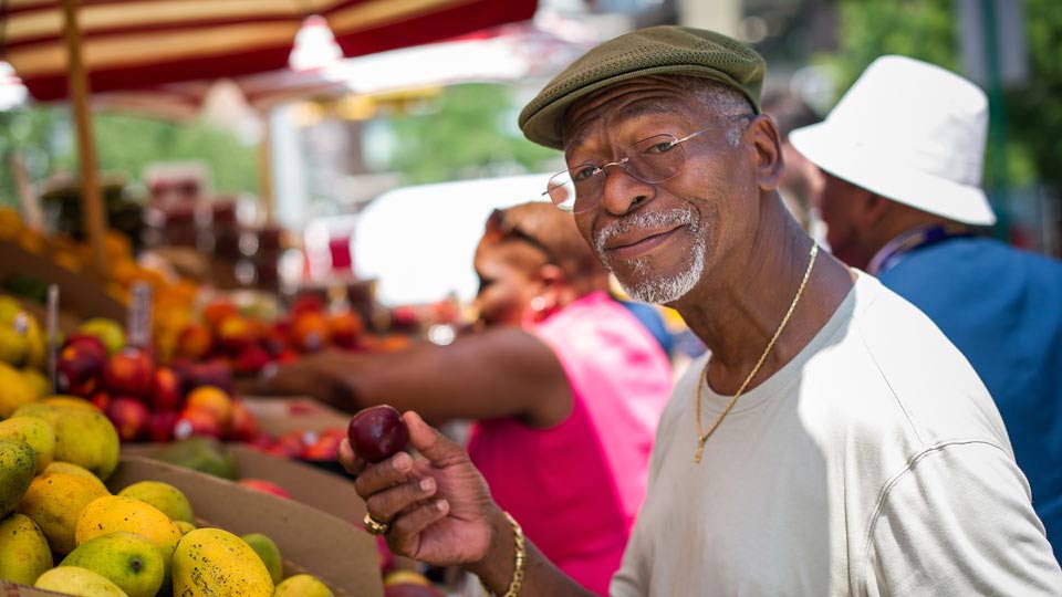 Man Holding Fruit at Fruit Stand