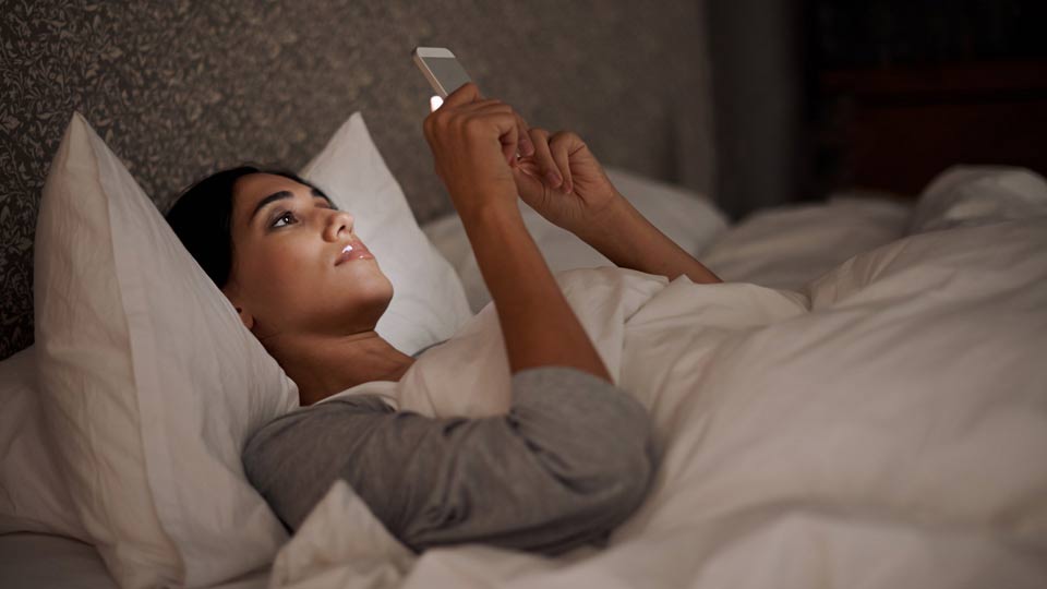 Woman Reading Her Phone in Bed