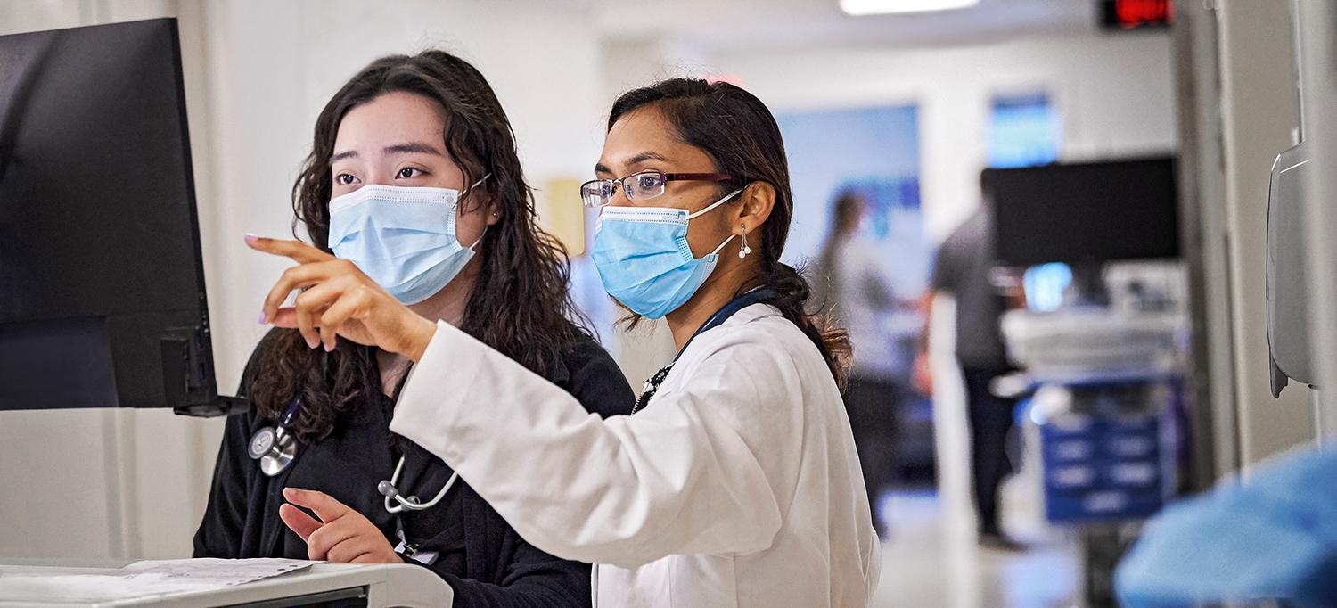 Dr. Stephanie Kong and Dr. Arundhati Das Wearing Face Masks and Reviewing Information on a Computer