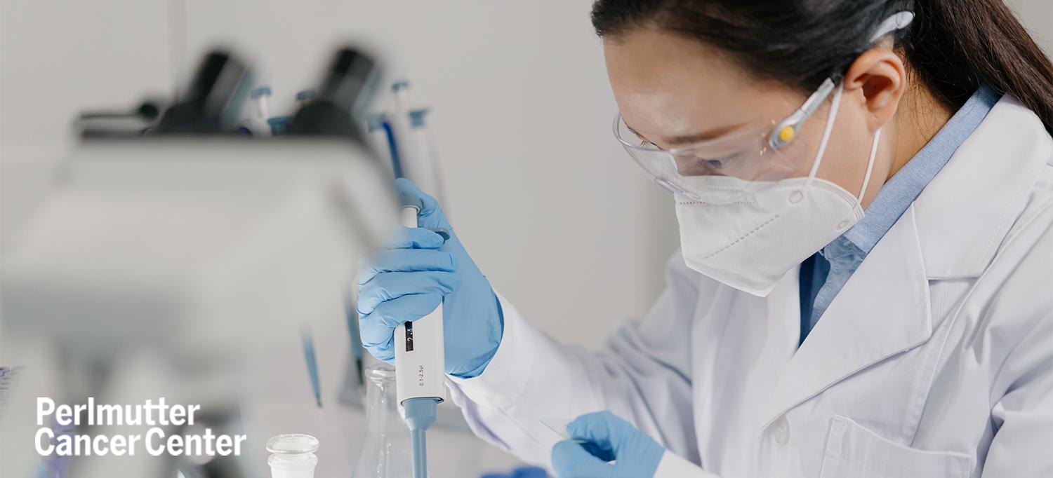 Scientist in Lab Wearing Protective Equipment and Using Pipette