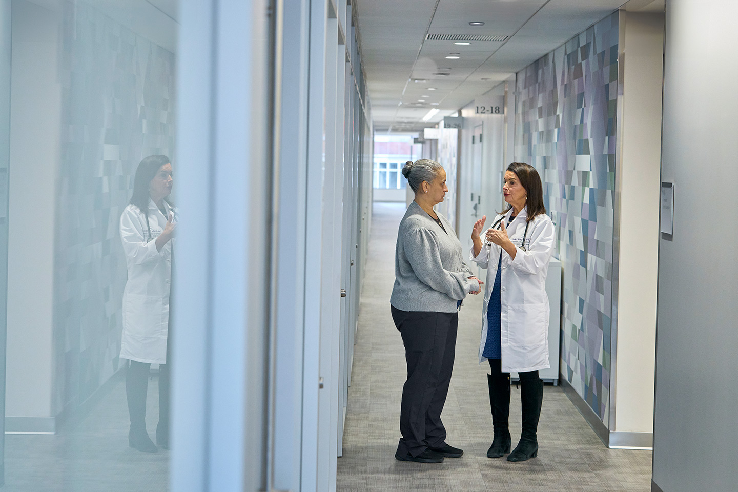 Nurse Practitioner Laurie Jeffers Talks With a Patient in a Hallway