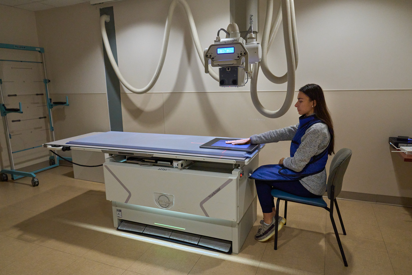 A woman sits with her hand on a medical scanner.