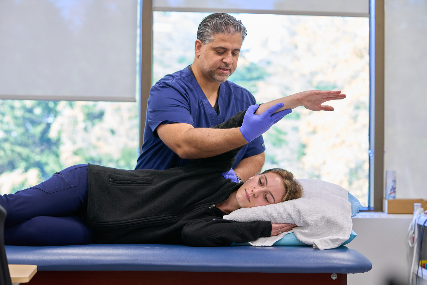 Occupational therapist Nesar Rabadi performs arm mobility exercises with a patient who is lying on an exam table.