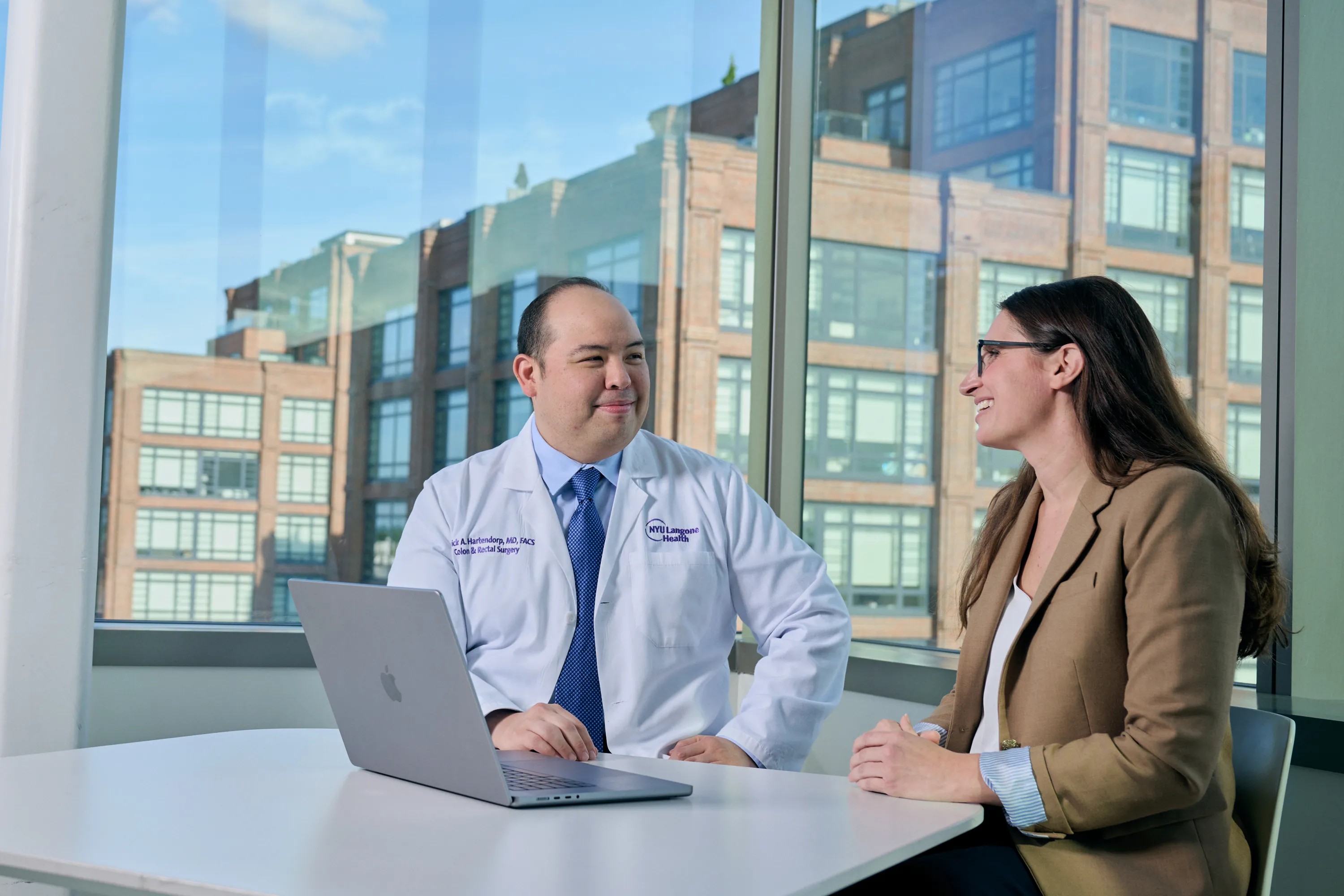 Dr. Patrick Hartendorp sits at a table with a laptop and smiles at a woman seated next to him.