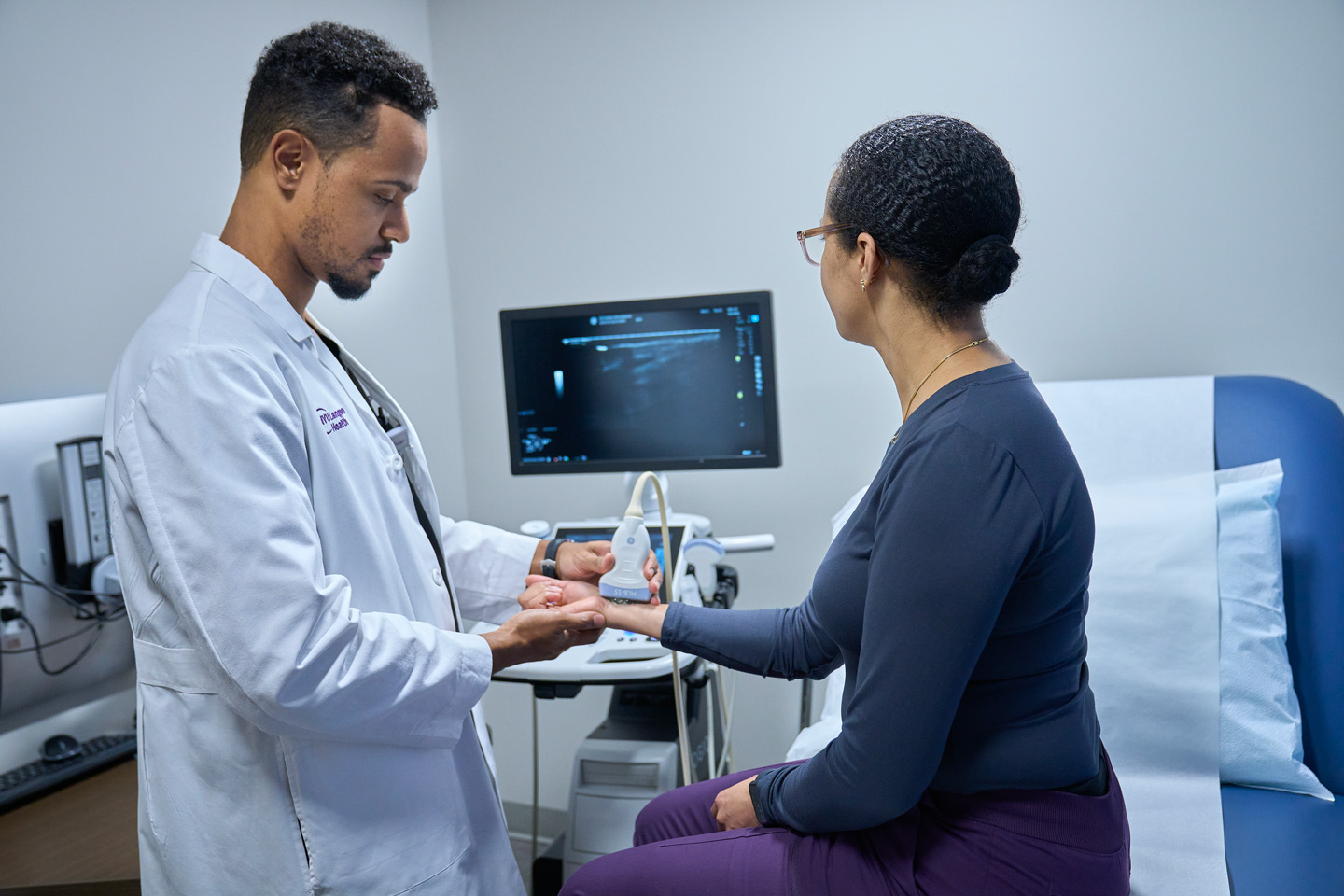 Dr. Willy Gonzalez images a patient’s wrist as she sits on an exam table.