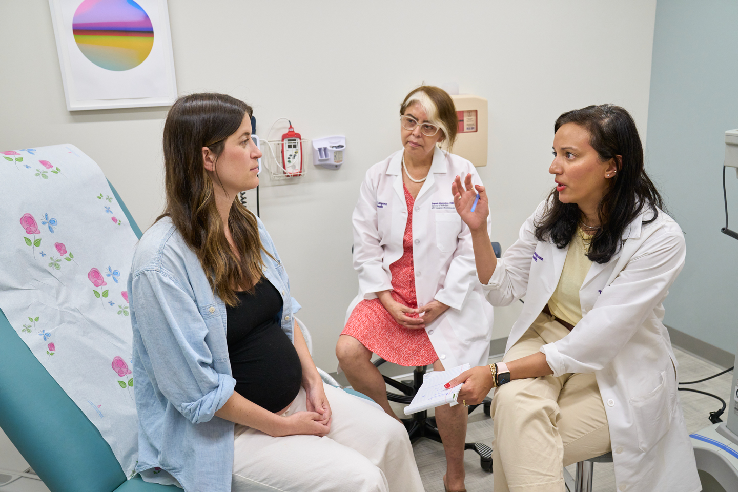 Midwife Eugenia Montesinos and Dr. Mahino Talib speaking with a patient in an exam room