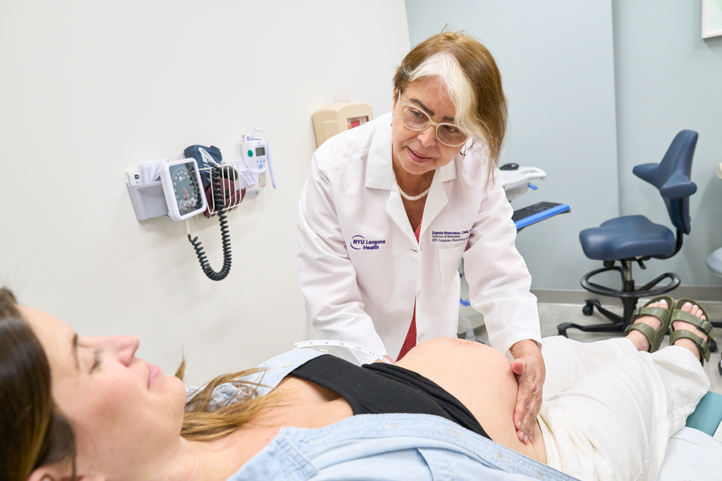 Midwife Eugenia Montesinos palpating the belly of a supine pregnant patient in an exam room