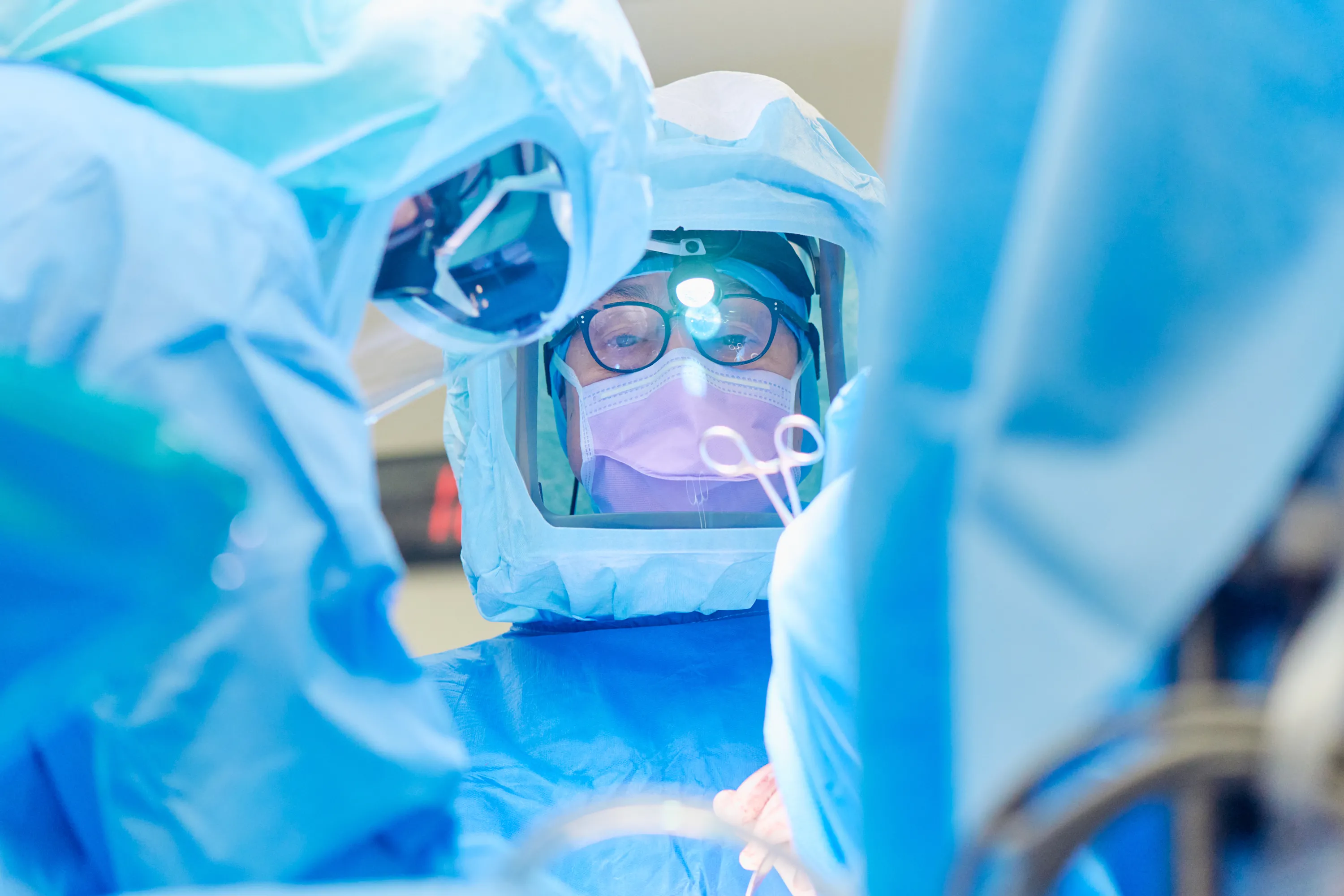 Dr. Nicola Fabbri and team in surgical suits and masks performing surgery in an operating room.