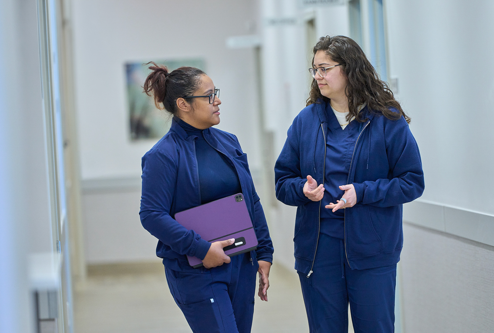 Two members of NYU Langone talk to each other in a hallway.