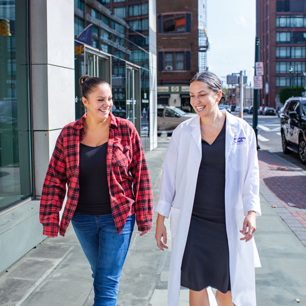 Smiling patient and provider talking together and walking down a city street