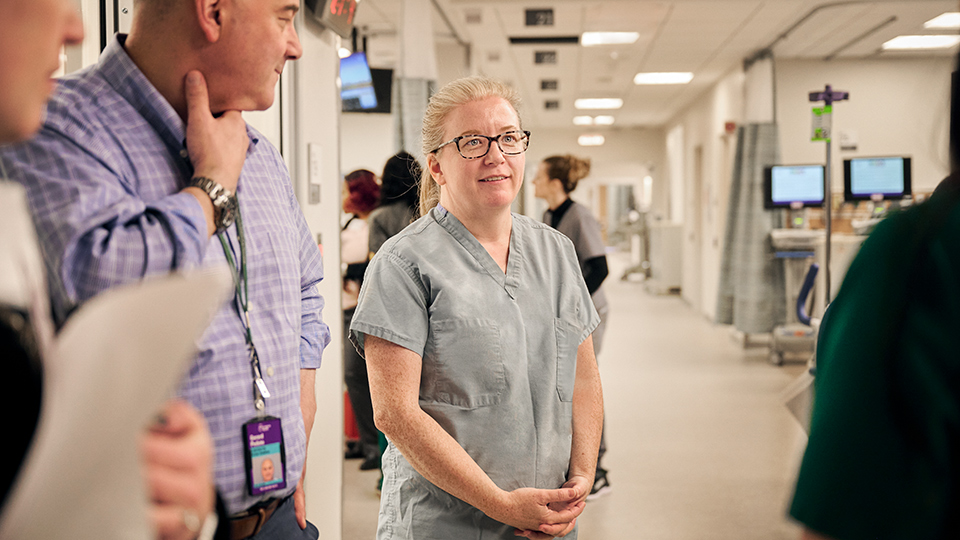 Doctor Stands in Emergency Department Surrounded by Colleagues