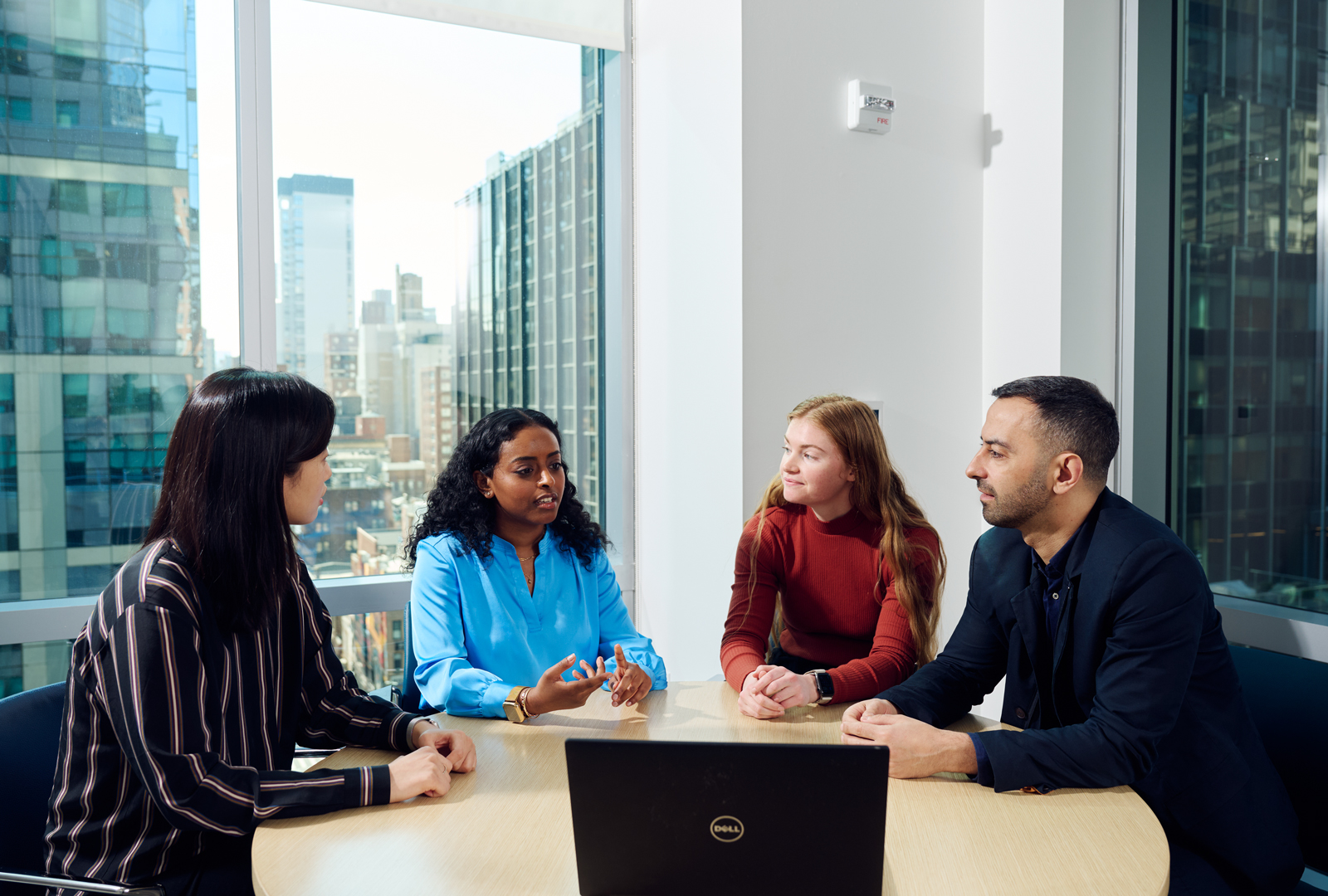 Four people seated around a table in conversation with one another in an office