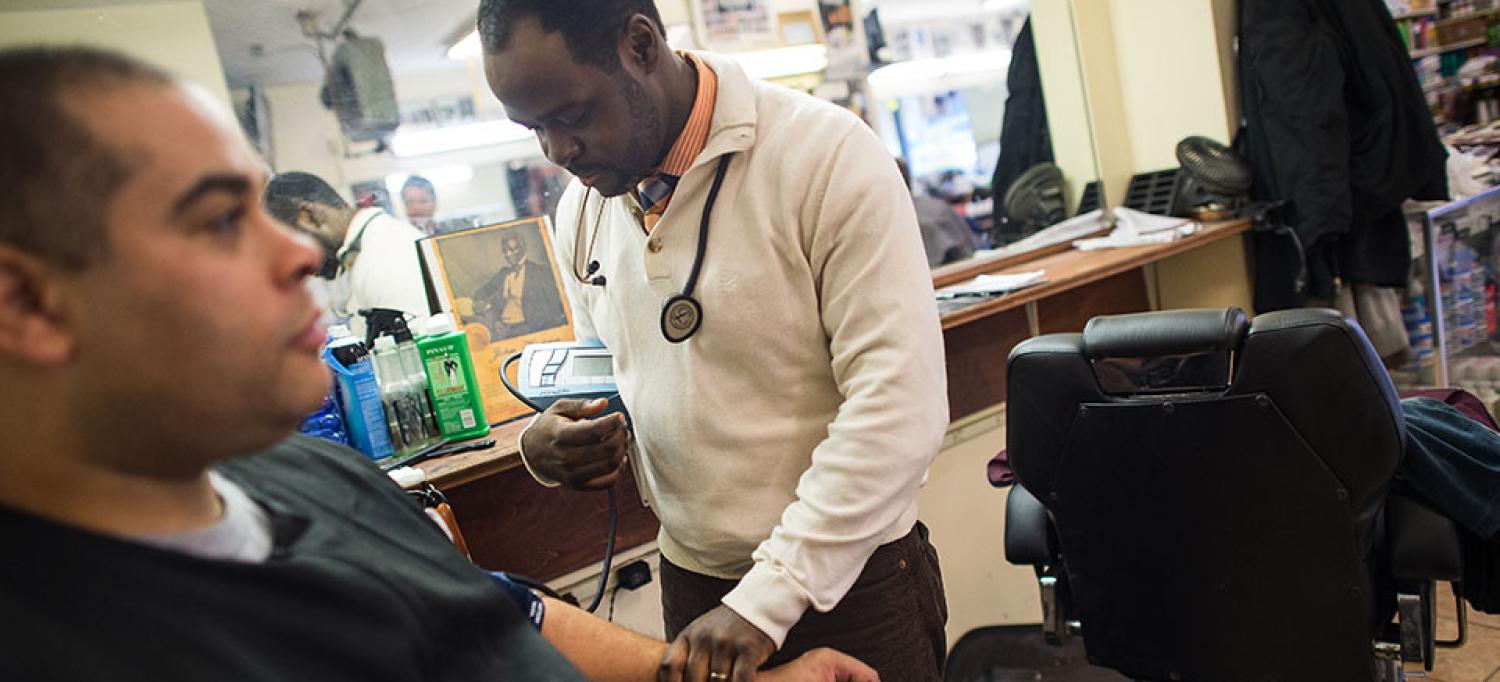 Dr. Joseph Ravenell Takes a Blood Pressure Reading From Man in Barbershop Chair