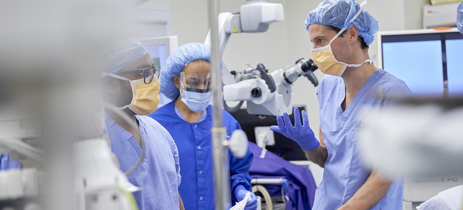 Dr. Michael R. Smith and Two Colleagues Talk in an Operating Room