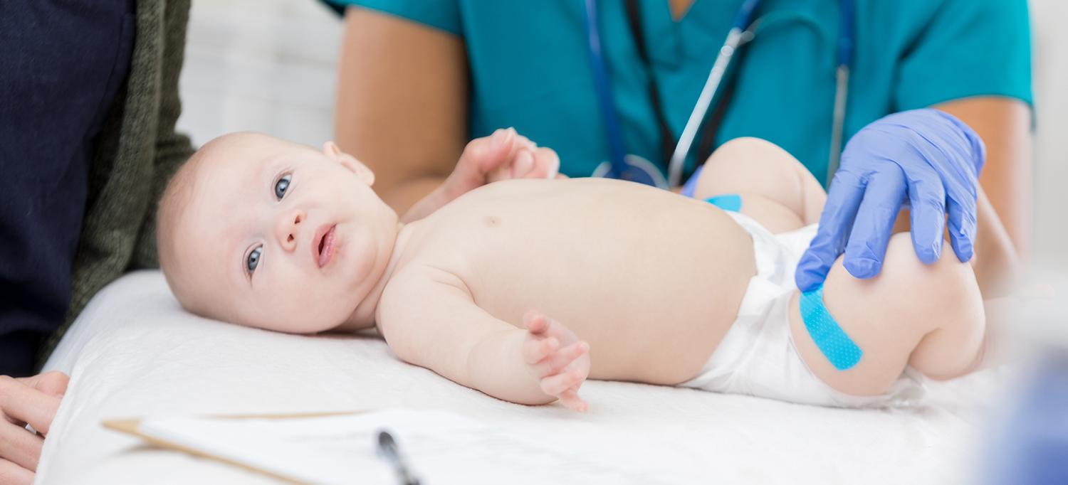 Pediatric Care Provider Places Adhesive Bandage on Baby’s Leg
