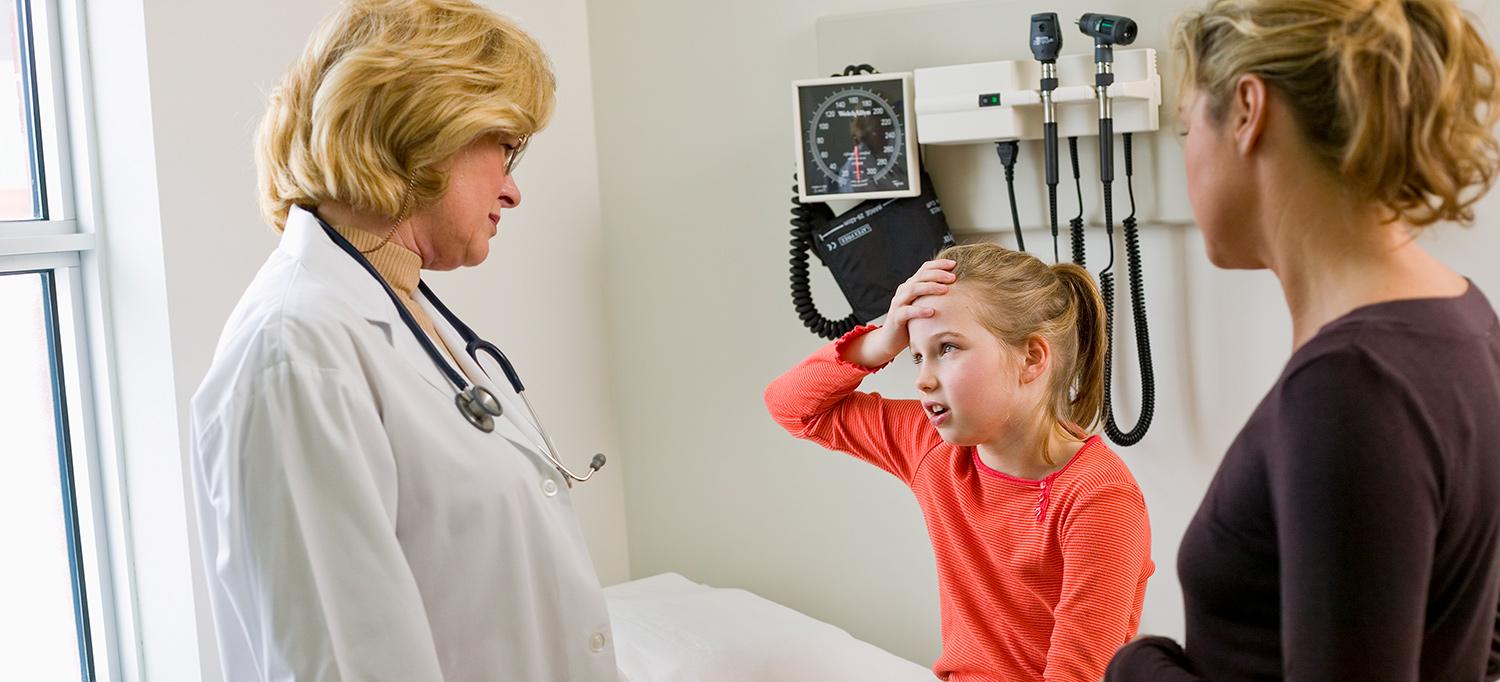 Young Girl with Hand on Her Head Speaks to Pediatrician