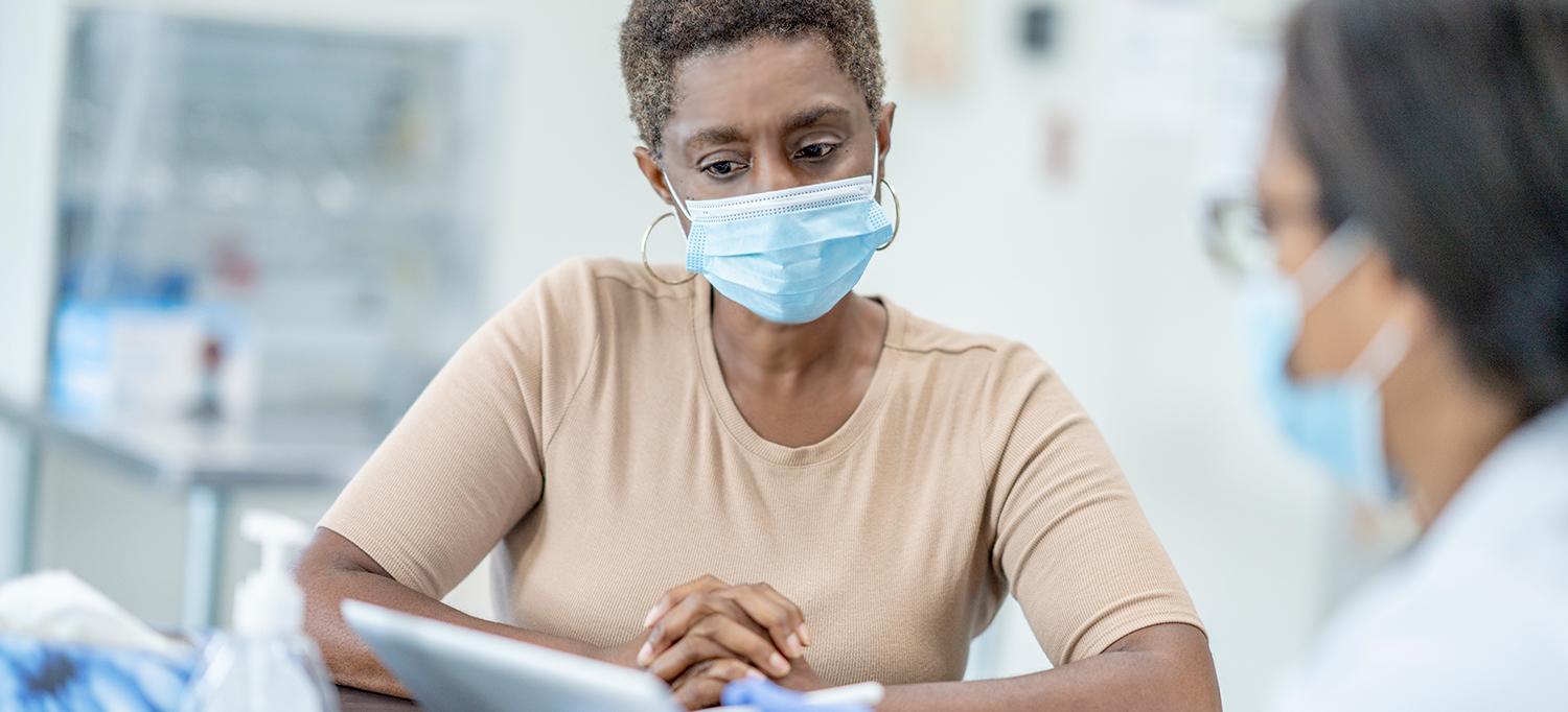 Woman Wearing Mask Speaks with Healthcare Provider Wearing Mask