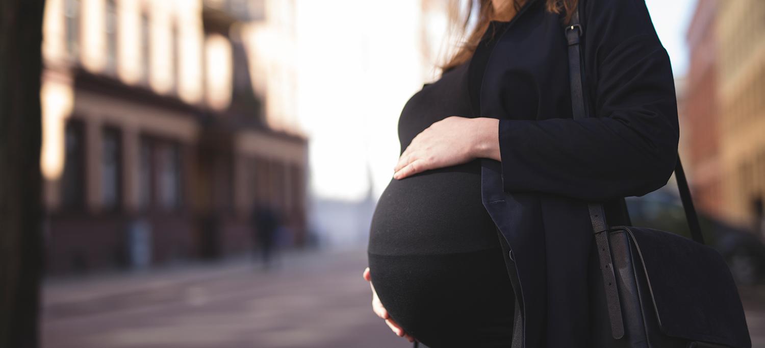 Pregnant Woman Standing on City Streetcorner