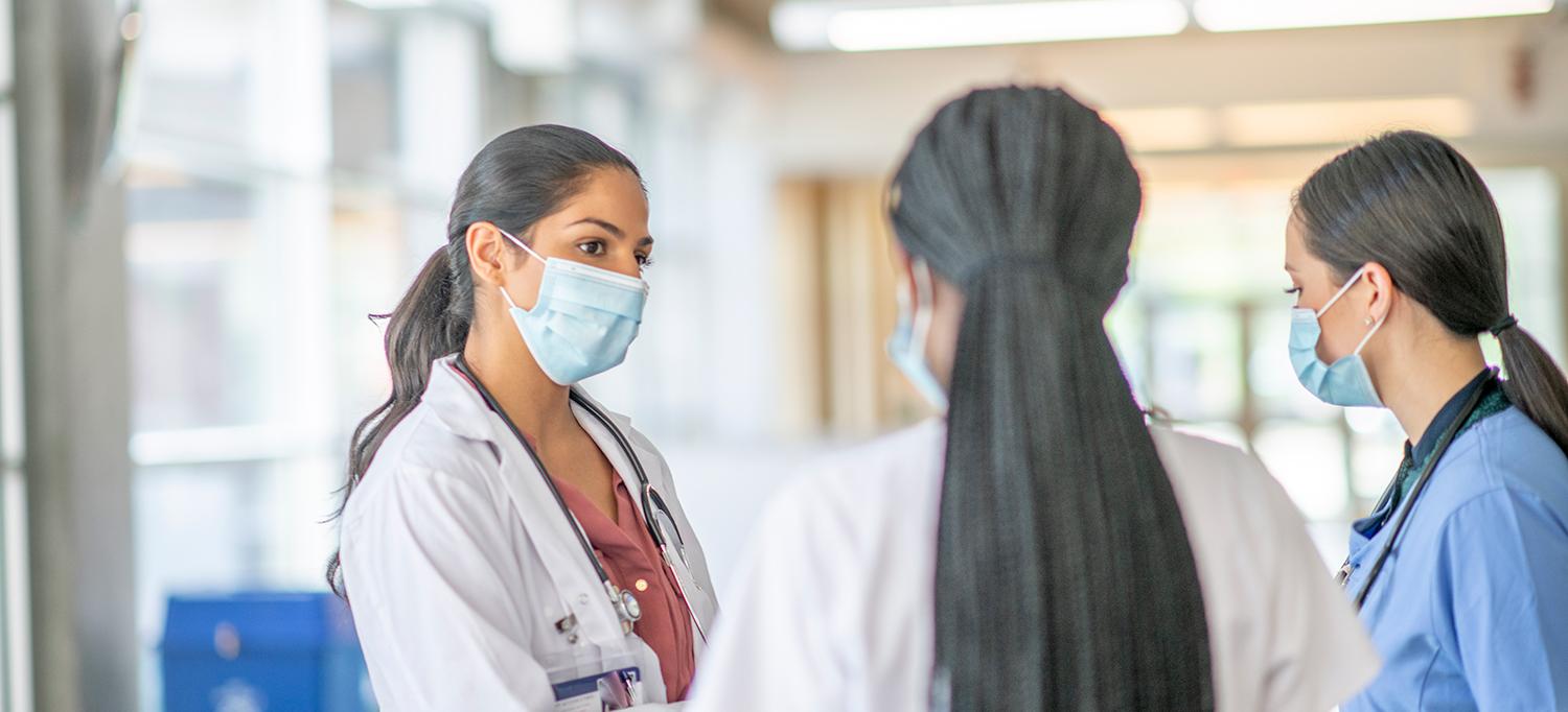 Three Healthcare Providers Wearing Masks in Hospital Hallway