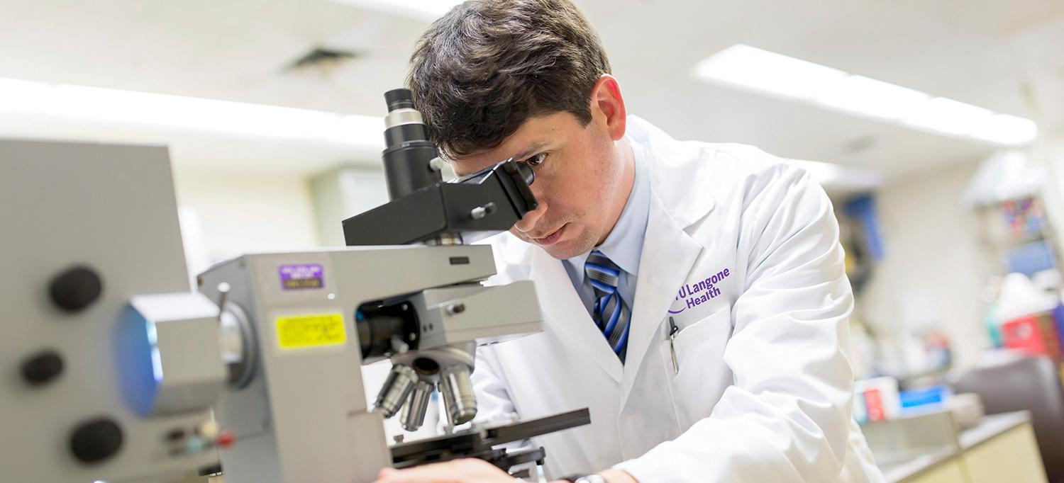 Dr. Leopoldo N. Segal Examines Specimen with Microscope in Lab