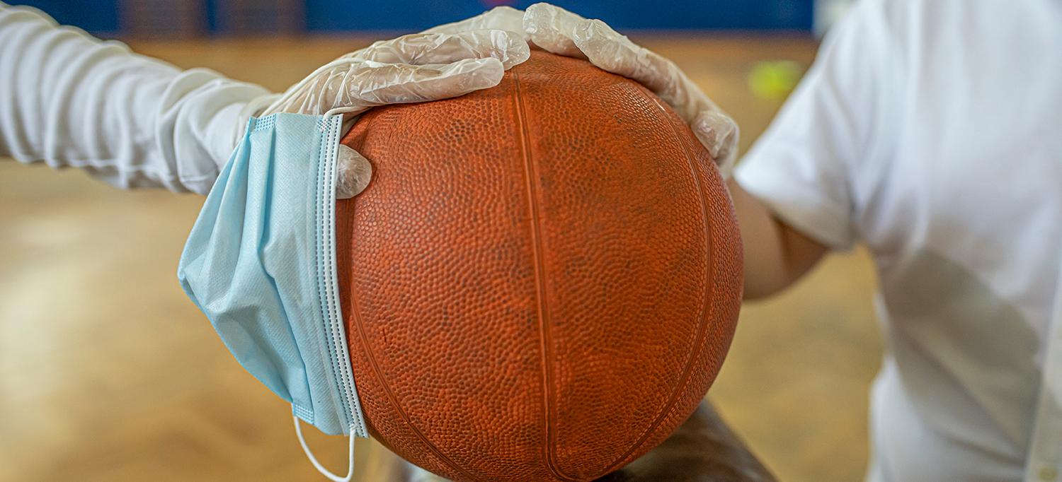 Two Gloved Hands Holding Face Mask and Basketball
