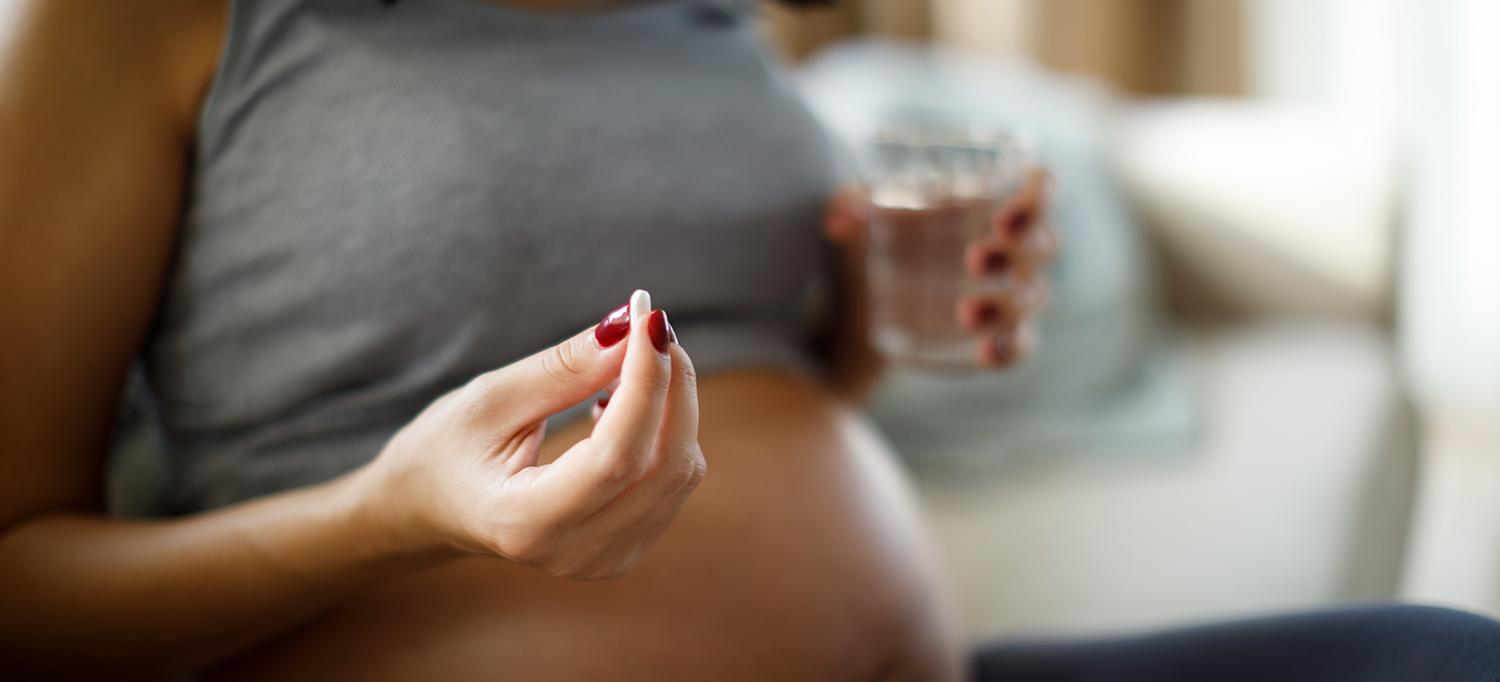 Pregnant Woman Holding Pill and Glass of Water
