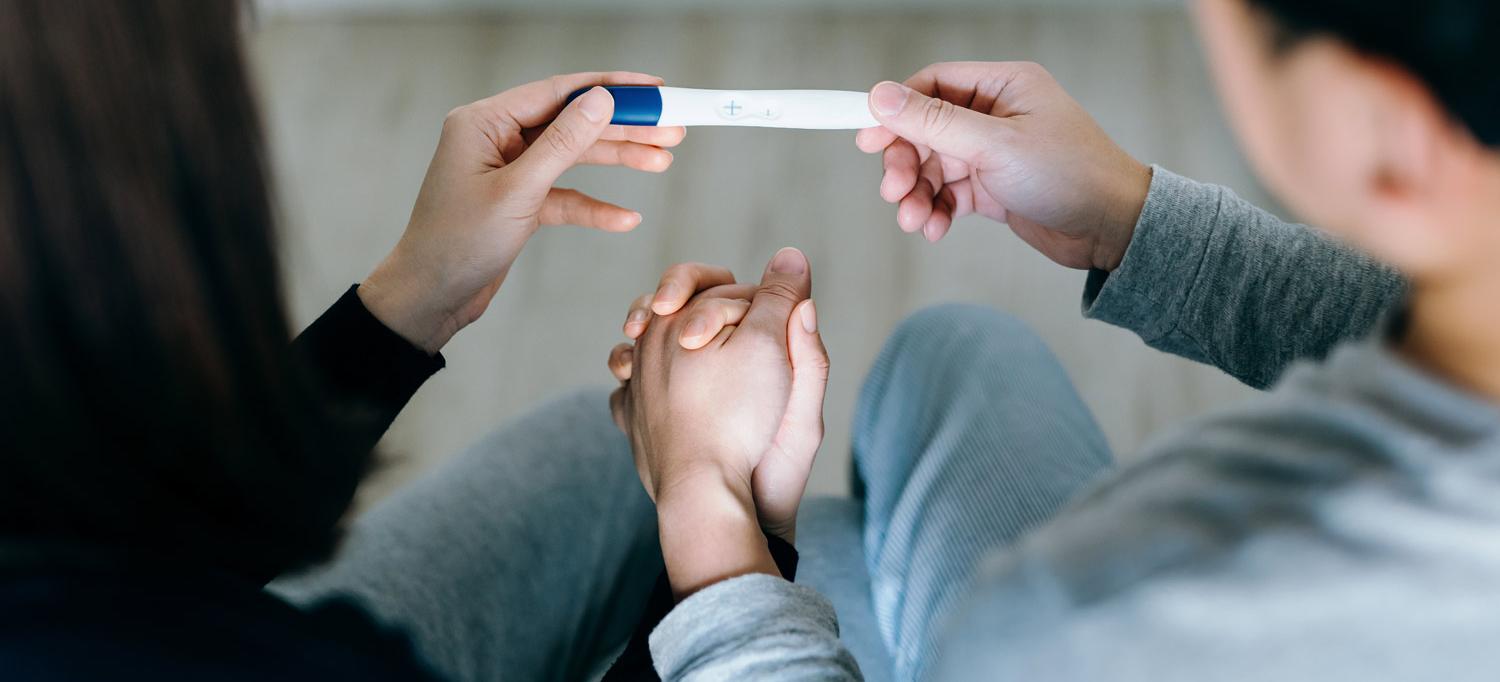 Couple Holding Hands and Pregnancy Test