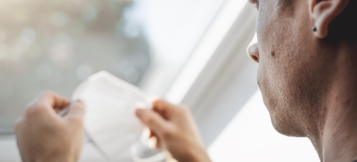 Person Holding Face Mask Looking Out Window