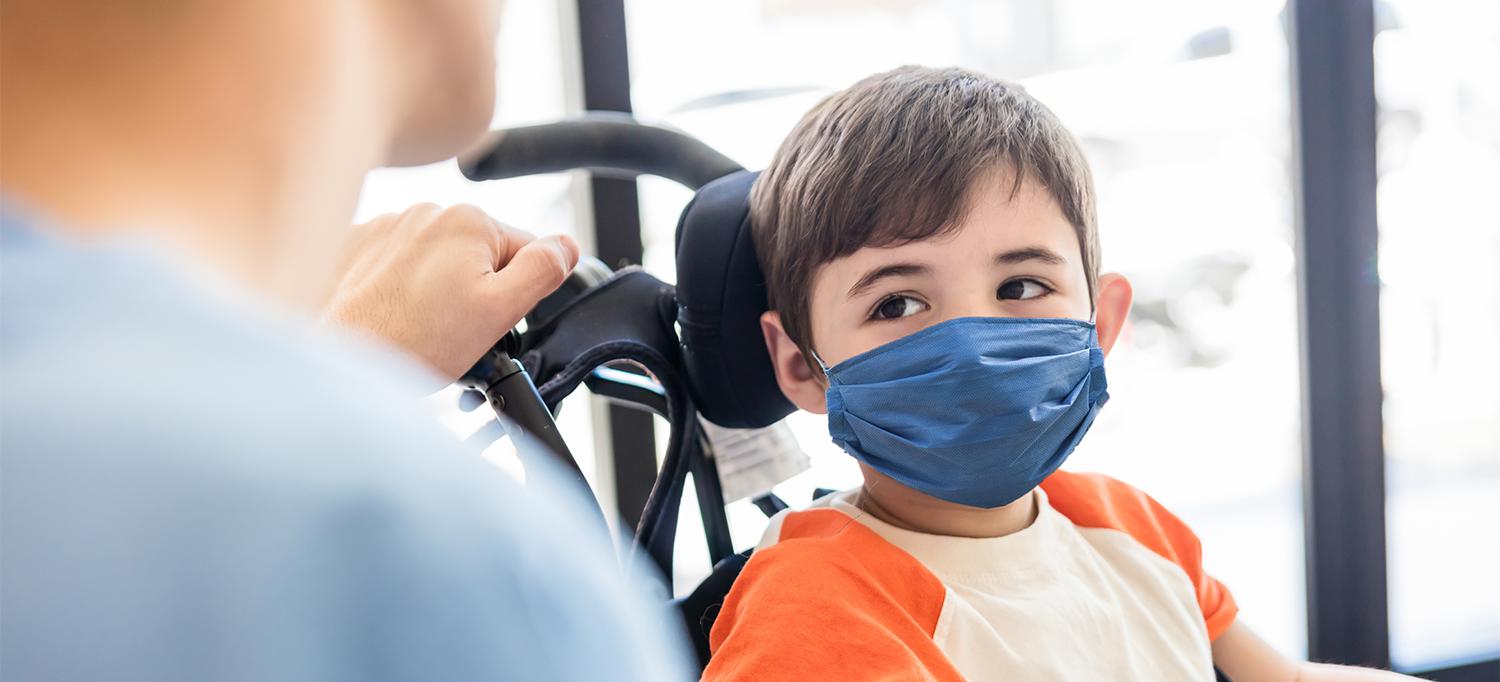 Young Boy Wearing Face Mask in Wheelchair