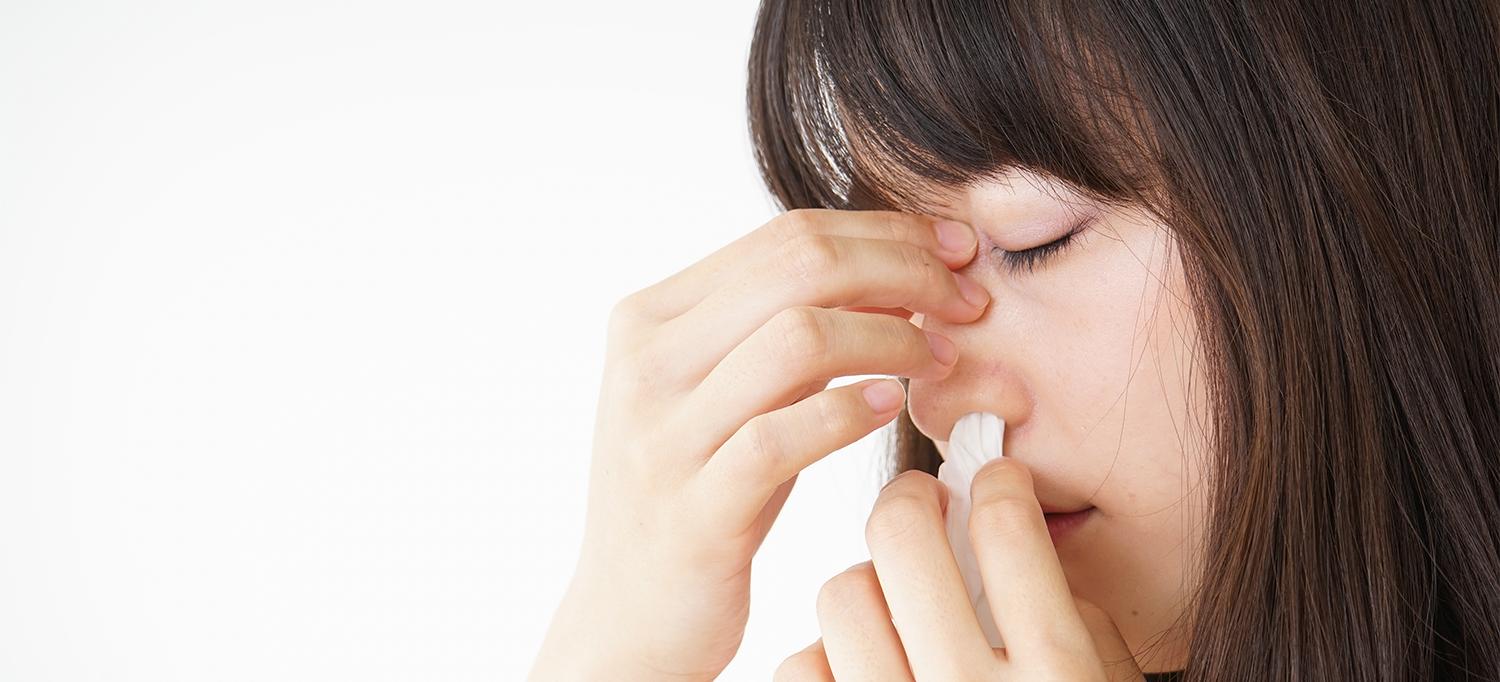 Person Holding Bridge of Nose and Putting Tissue in Nostril