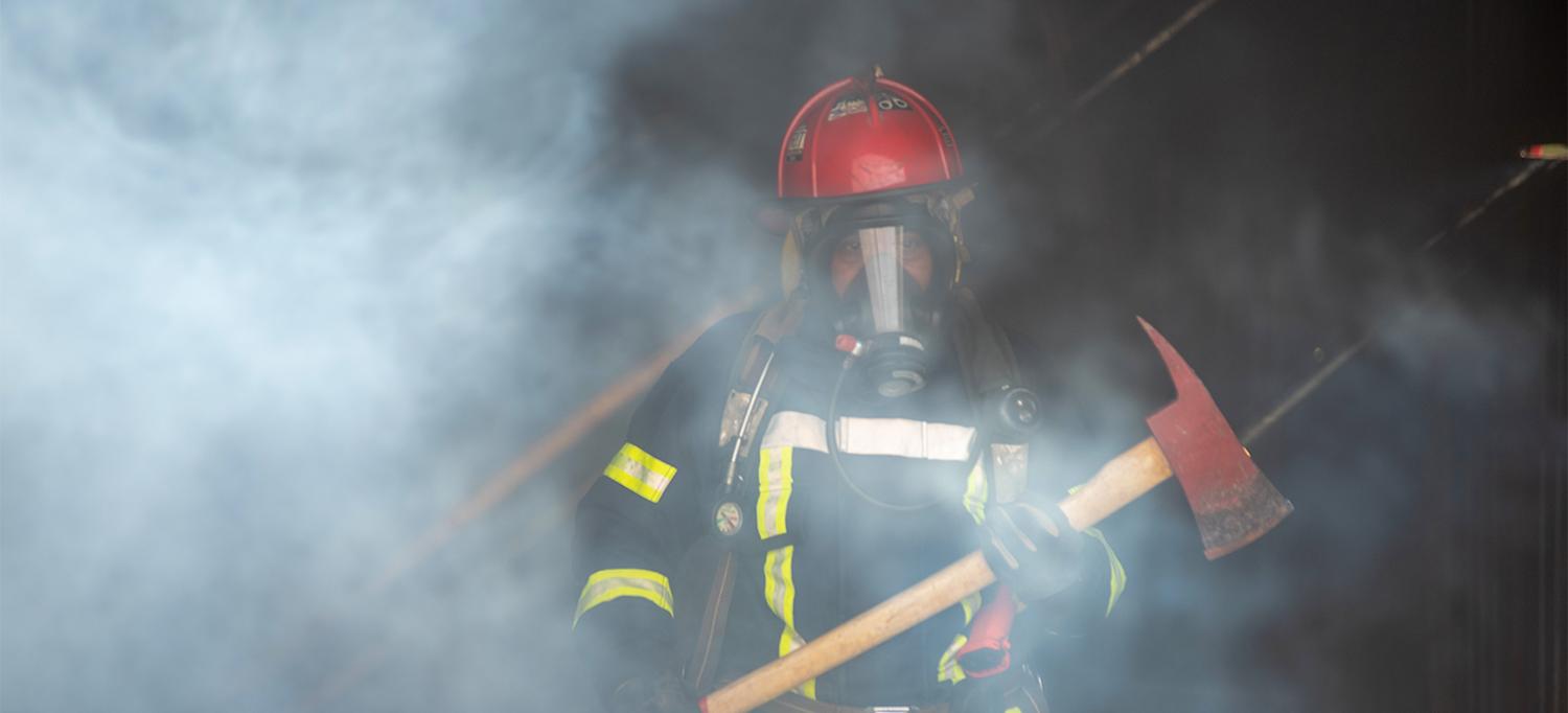Firefighter Wearing Gear and Holding Axe in Smokey Building