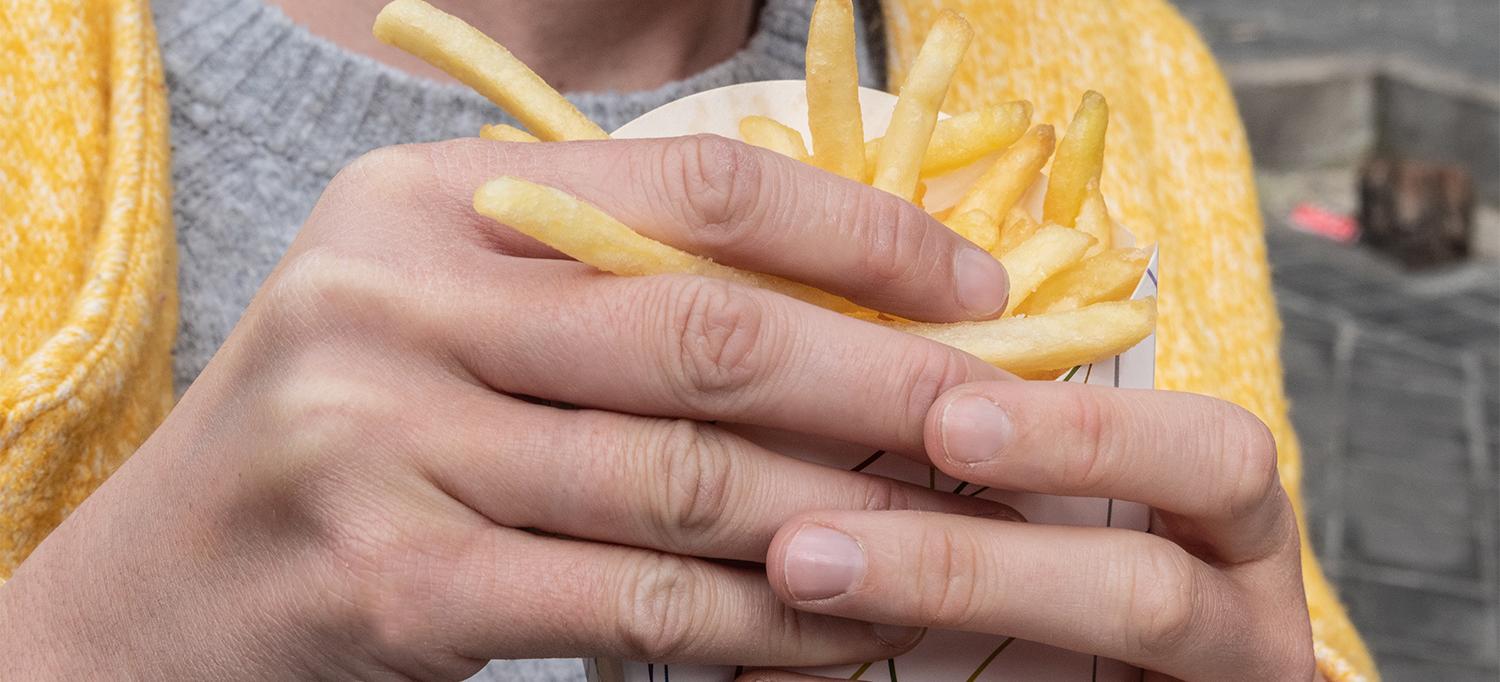 Person Holding a Box of French Fries