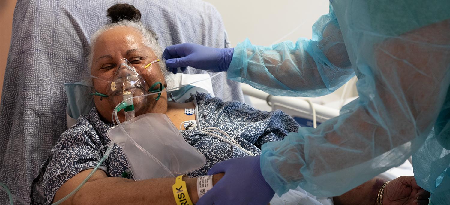 Healthcare Provider Tends to Patient Wearing Oxygen Mask