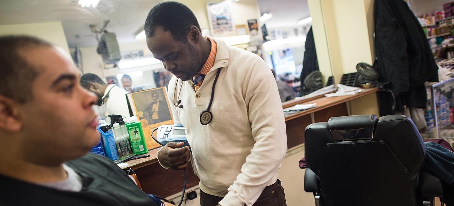 Dr. Joseph E. Ravenell Measures Man’s Blood Pressure in Barbershop