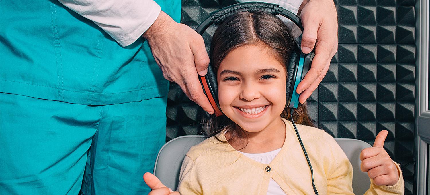 Doctor Puts Headphones on Child for Hearing Test