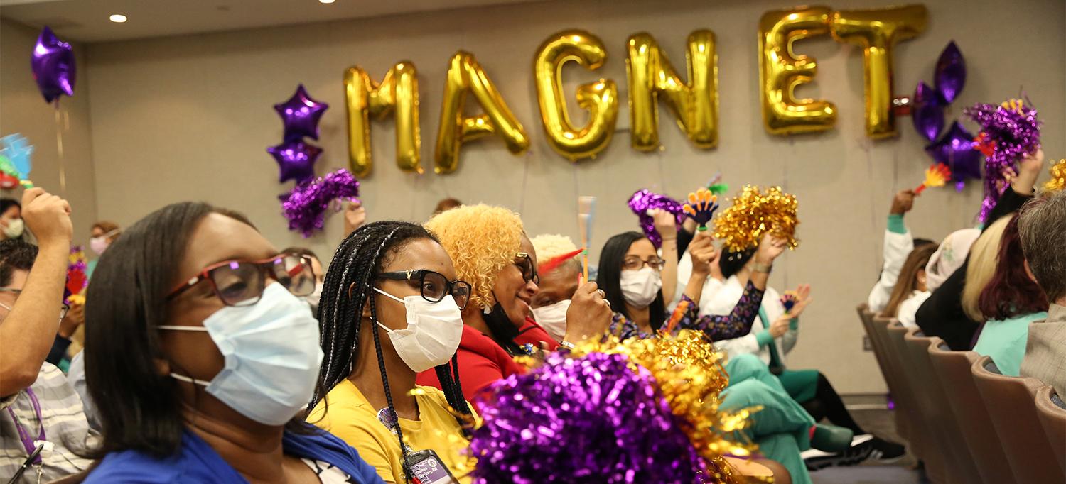 Staff at NYU Langone Hospital—Brooklyn Celebrating the Recognition with Purple and Gold Pom-Poms and Balloons That Spell “MAGNET”
