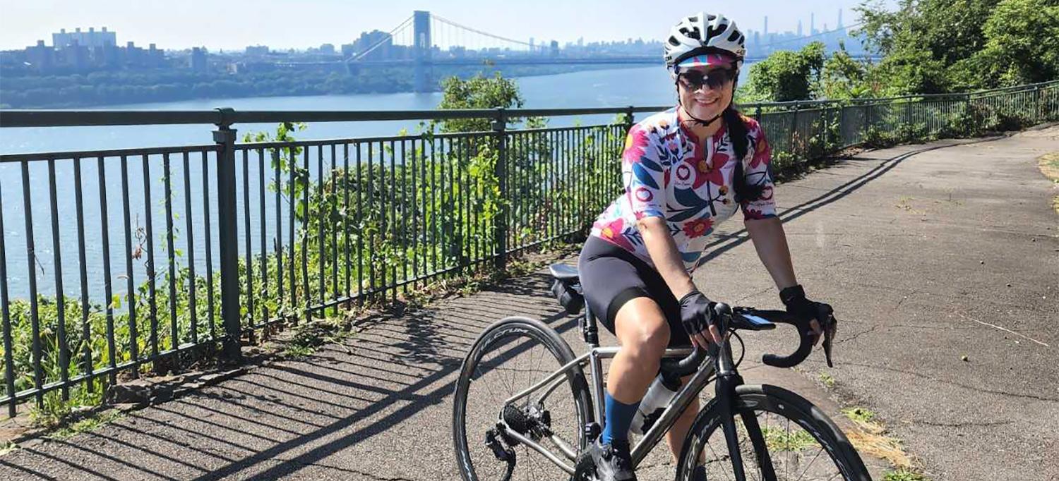 Nuria Flores on Her Bike on a Path Overlooking a River and the City