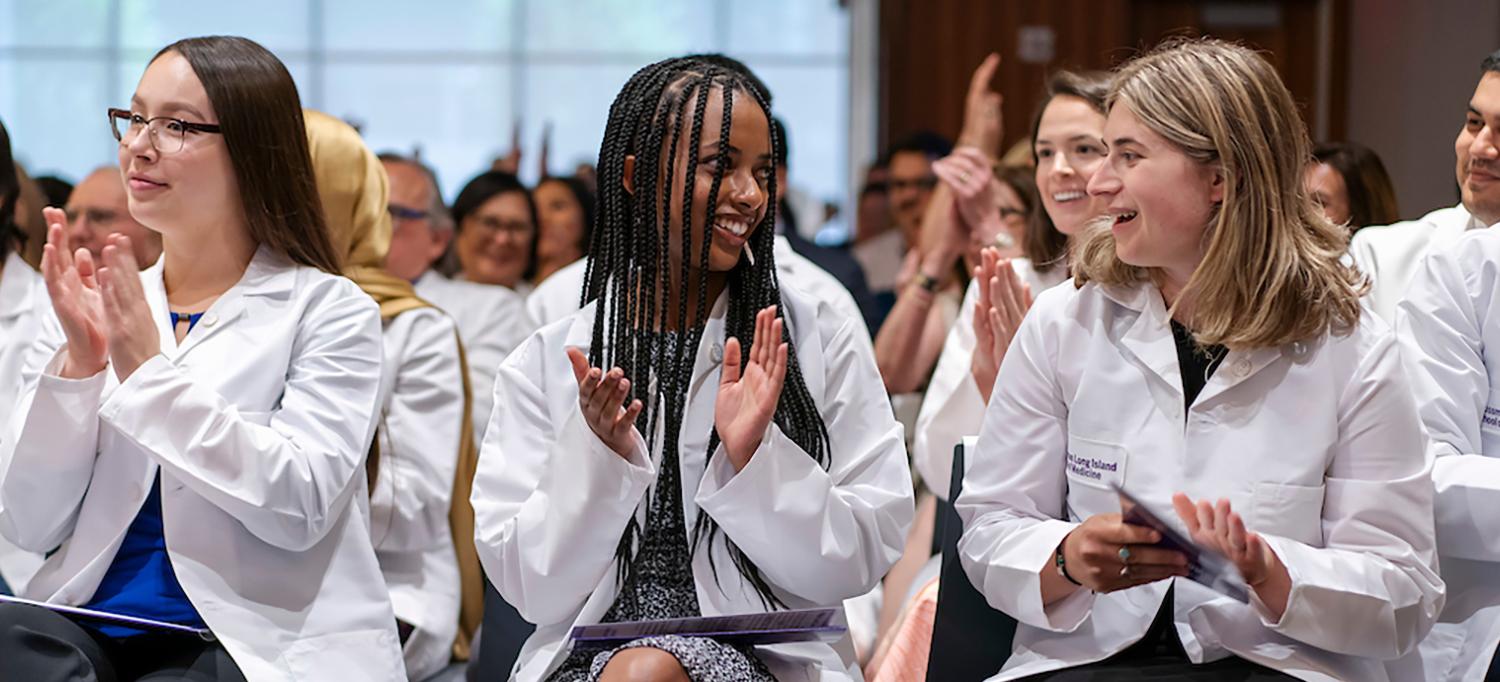 Close-Up View of Medical Students in White Coats Clapping and Smiling at One Another