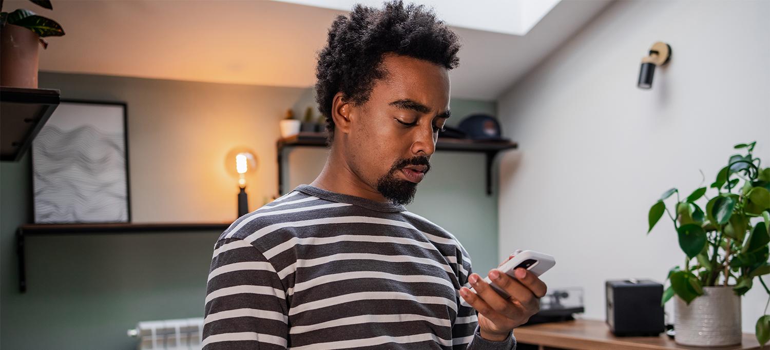 Black Man Looking Down at Smartphone Screen