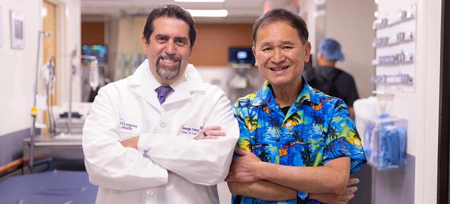 Dr. George Fernaine and Tak Yuen stand next to each other with their arms folded in a hospital corridor