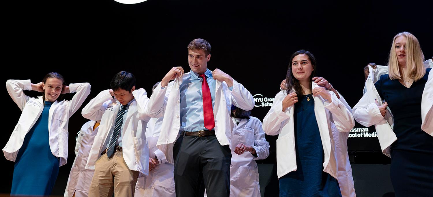 New medical students being helped into their white coats during the ceremony.