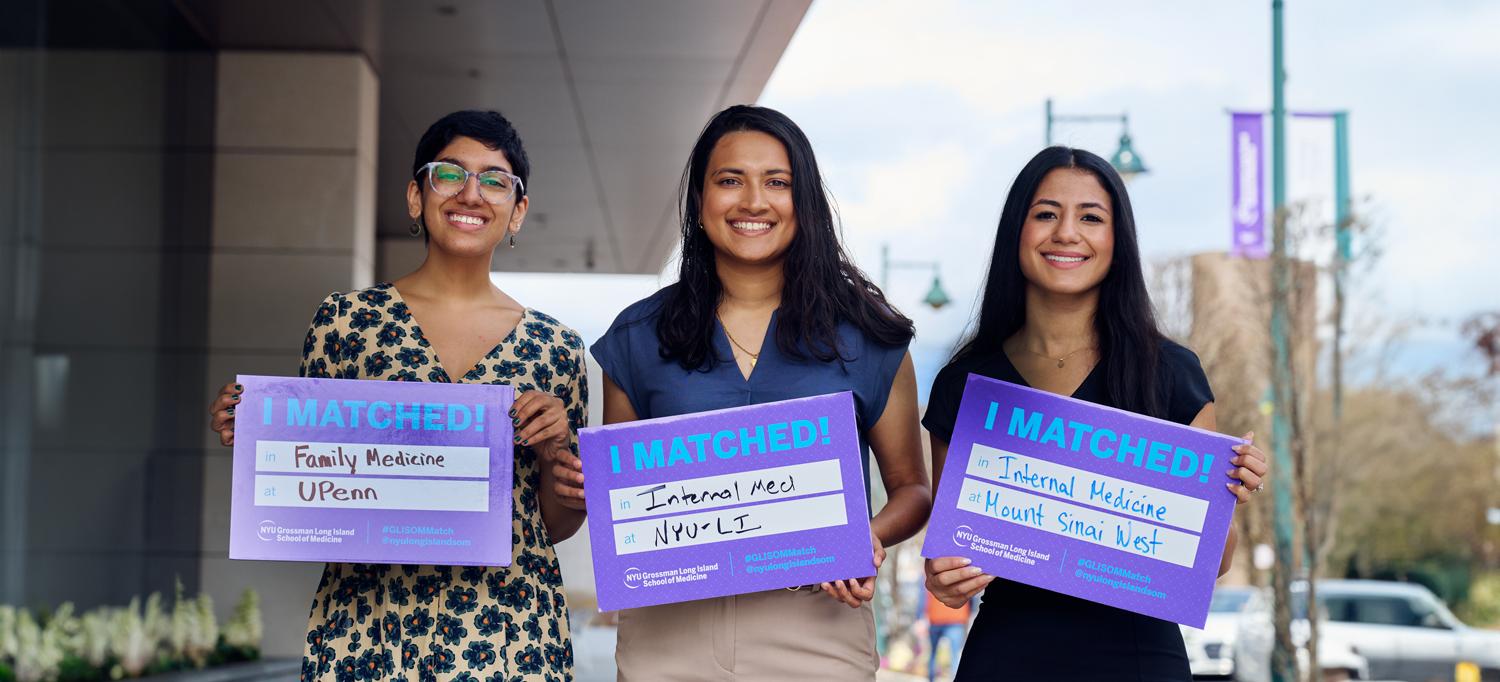 Three smiling students holding cards showing where they've matched for residency training