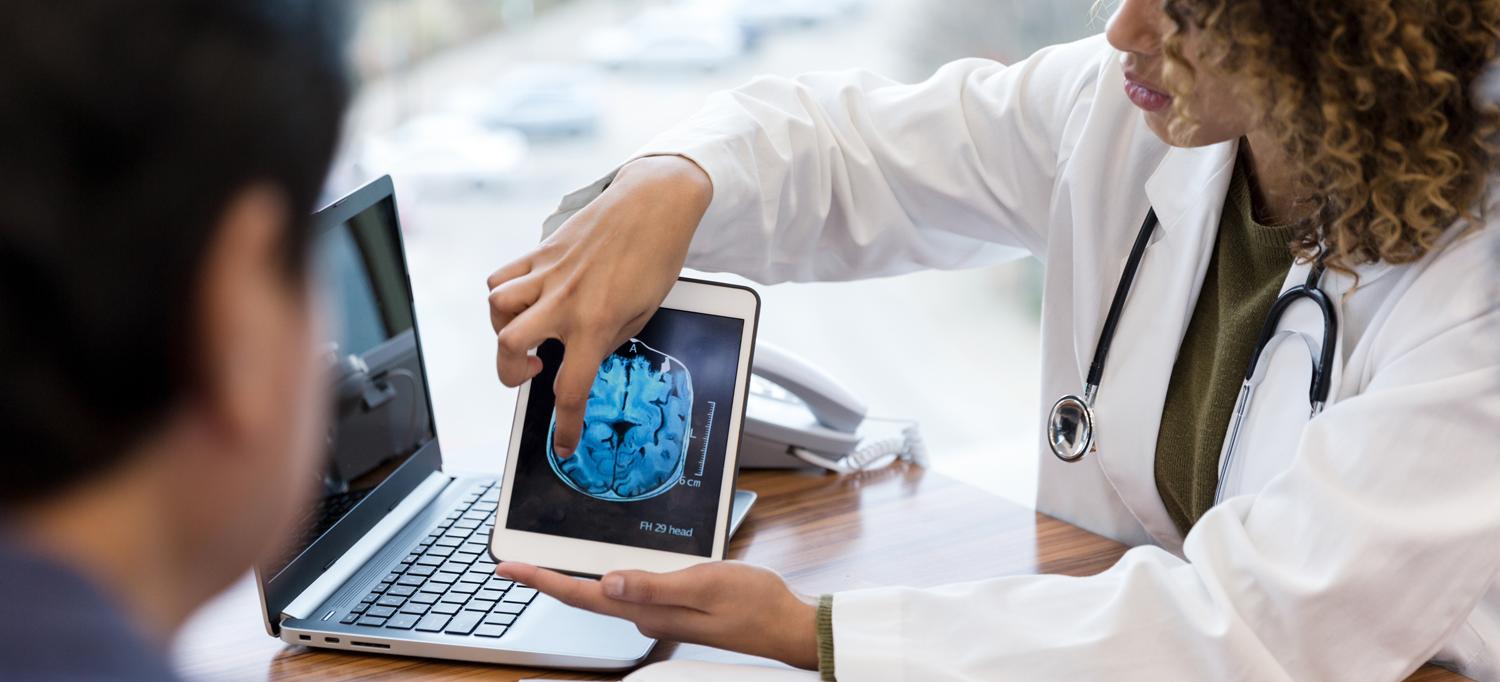 A doctor using a tablet to show a brain scan to a patient