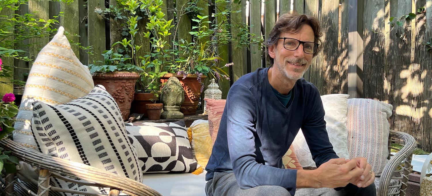 Stuart Ohleyer sits on a chair in a leafy backyard.