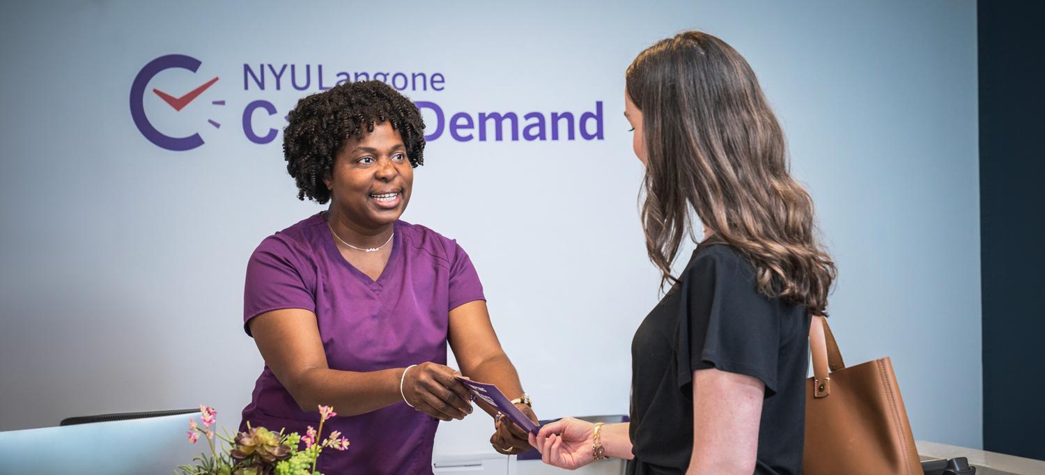 Smiling woman at front desk helps patient check in at Care on Demand location