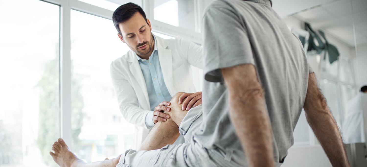 Older man having his knee examined by a doctor