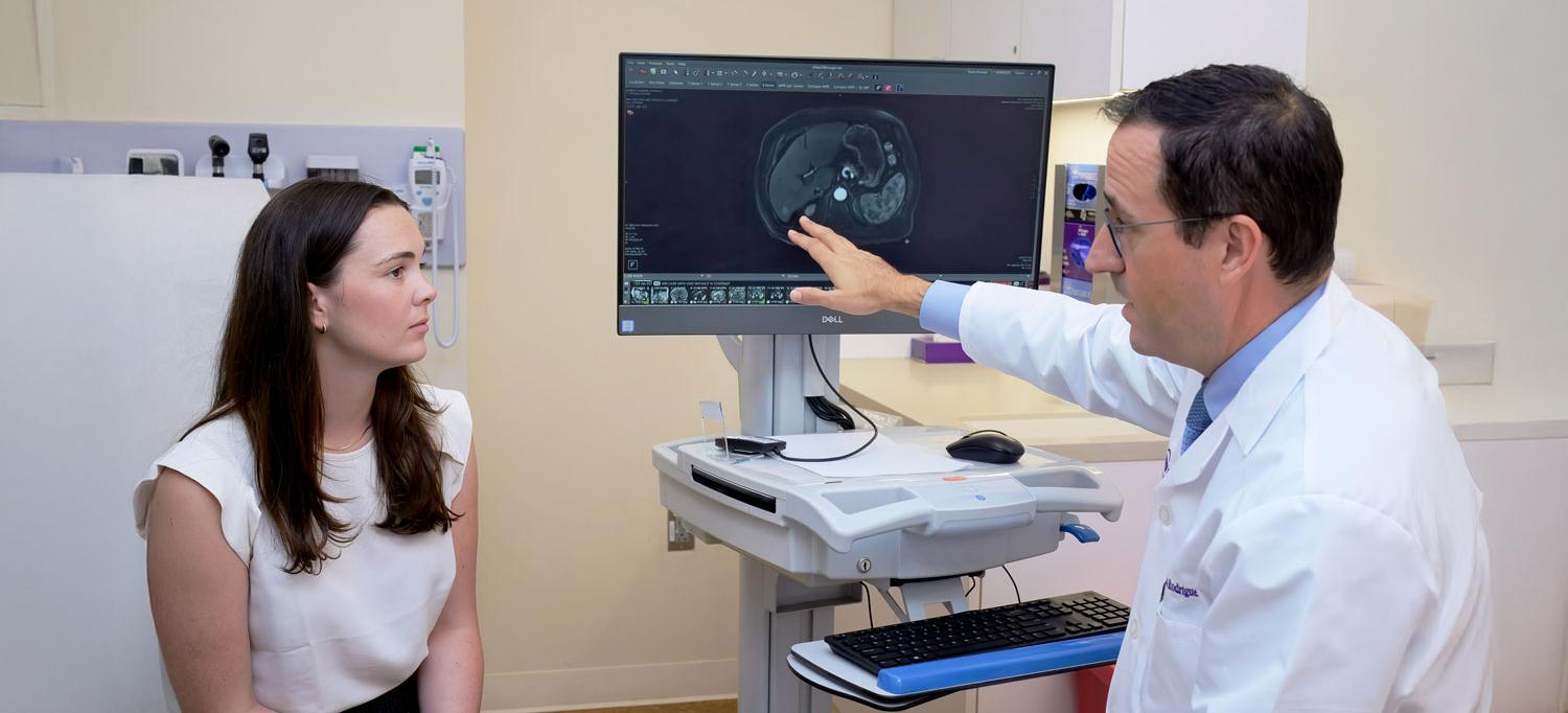 Dr. Augusto Villanueva Rodriguez reviews a scan with a patient.