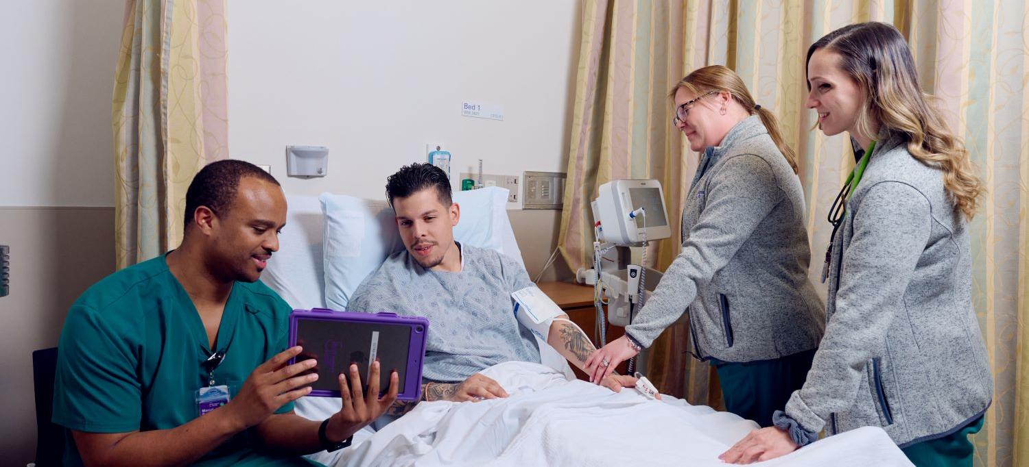People gather around a patient in a hospital bed. 