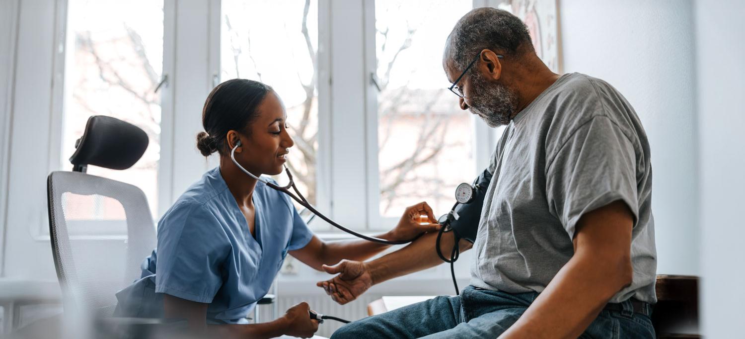 A doctor checks a senior patient's blood pressure in exam room at hospital