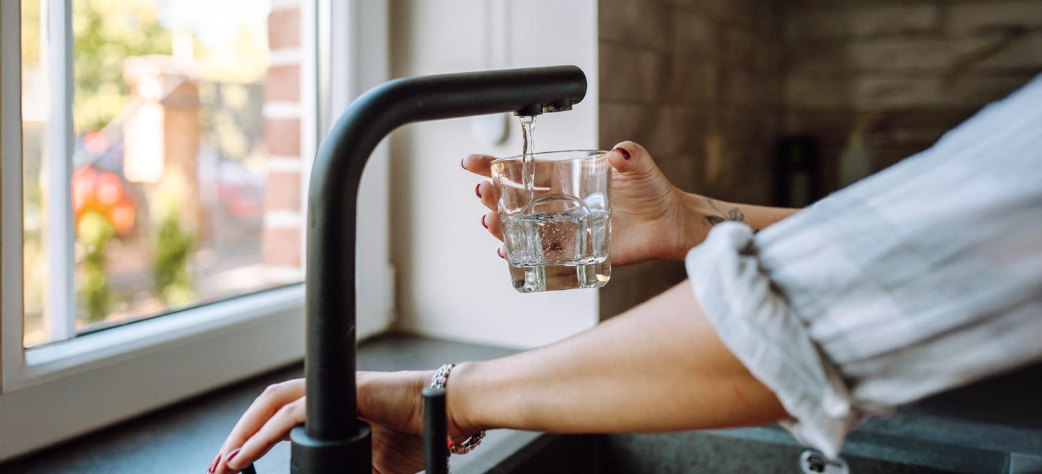 A woman fills a glass of water from a tap